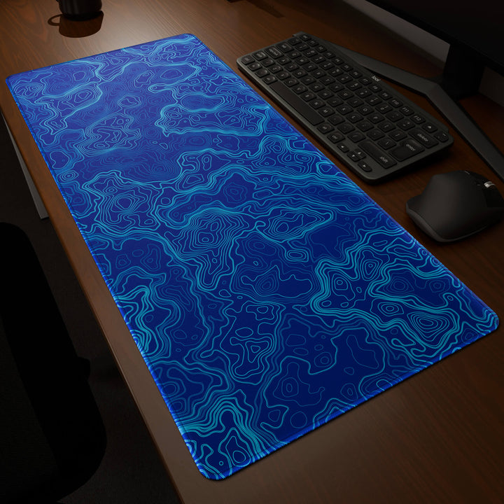 Dynamic angled perspective of a 90x40CM / 35x15.7in large mouse pad / desk mat featuring the vivid 'Blue Topographic' design, inspired by blue minimalist topographic art. Its generous dimensions offer a vast, smooth area that protects your desk while enhancing mouse glide and overall comfort.