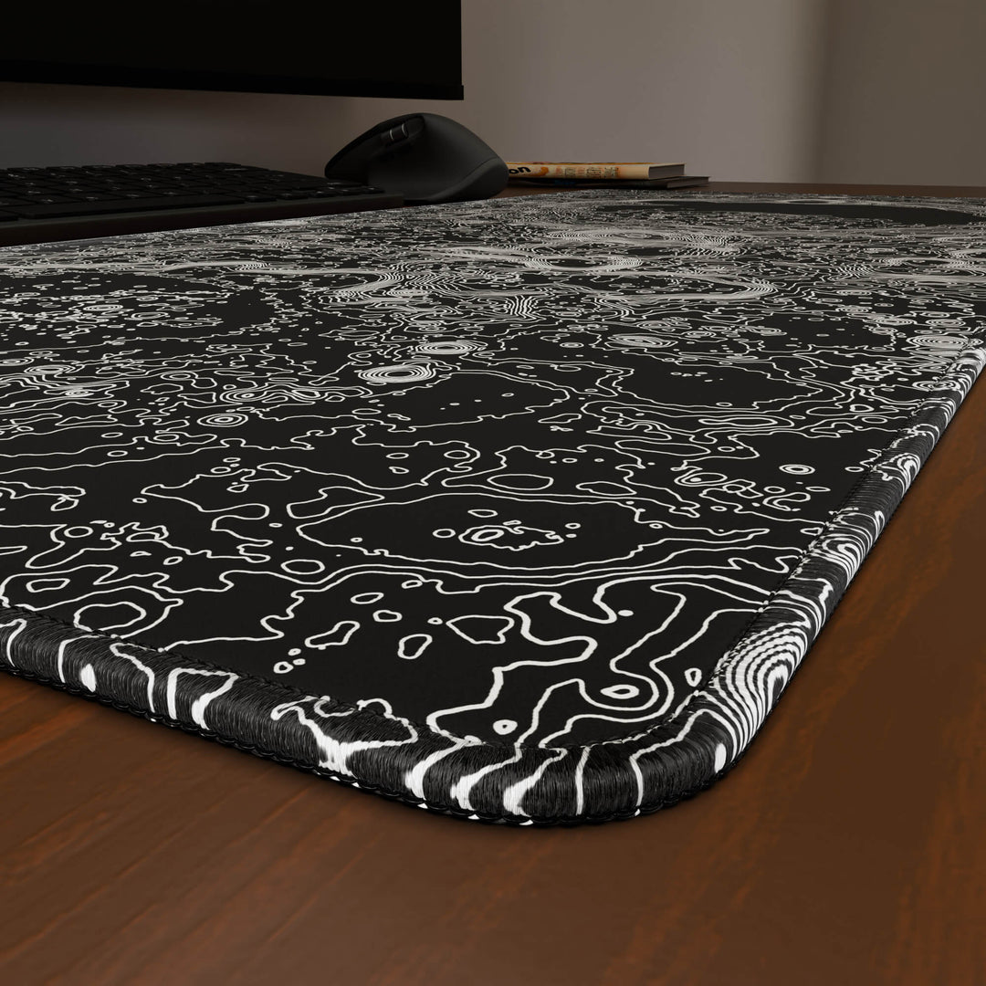 Close-up angled shot highlighting the durable stitched edges of a 90x40CM / 35x15.7in large mouse pad / desk mat with the 'Lunar Topographic' design, inspired by minimalist lunar surface art. The reinforced stitching prevents fraying, ensuring long-lasting durability and a consistently clean aesthetic.