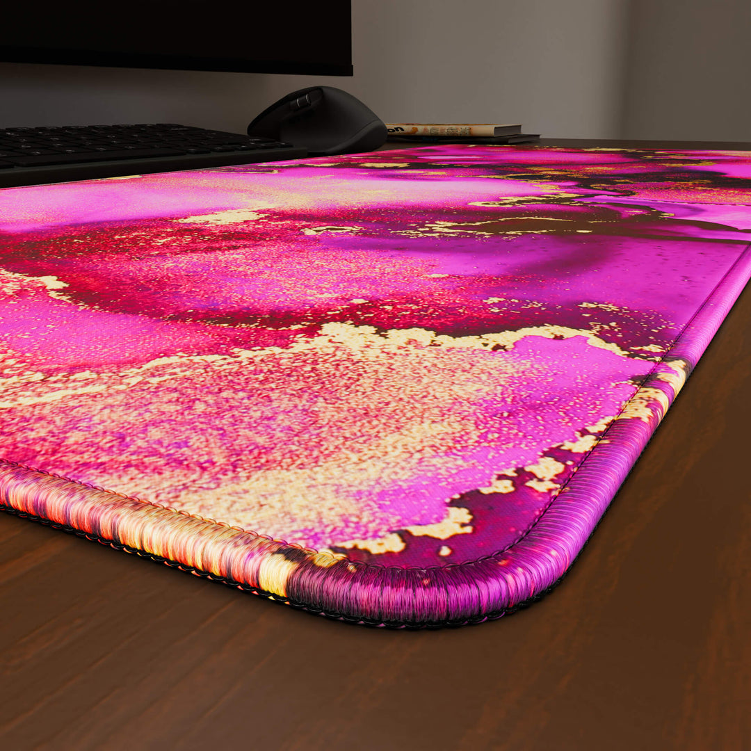 Close-up angled shot highlighting the durable stitched edges of a 90x40CM / 35x15.7in large mouse pad / desk mat with the 'Pink & Gold' design, inspired by pink and gold alcohol ink art. The reinforced stitching prevents fraying, ensuring long-lasting durability and a consistently clean aesthetic.