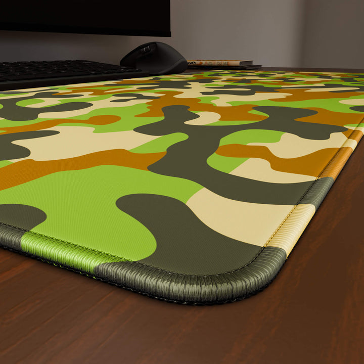 Close-up angled shot highlighting the durable stitched edges of a 90x40CM / 35x15.7in large mouse pad / desk mat with the 'Woodland Camo' design, inspired by a classic woodland camouflage pattern. The reinforced stitching prevents fraying, ensuring long-lasting durability and a consistently clean aesthetic.